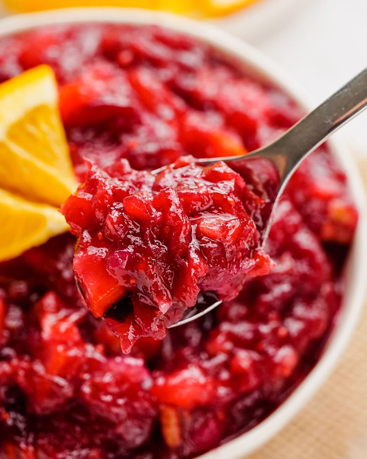 A spoonful of cranberry orange sauce hovering above the bowl.