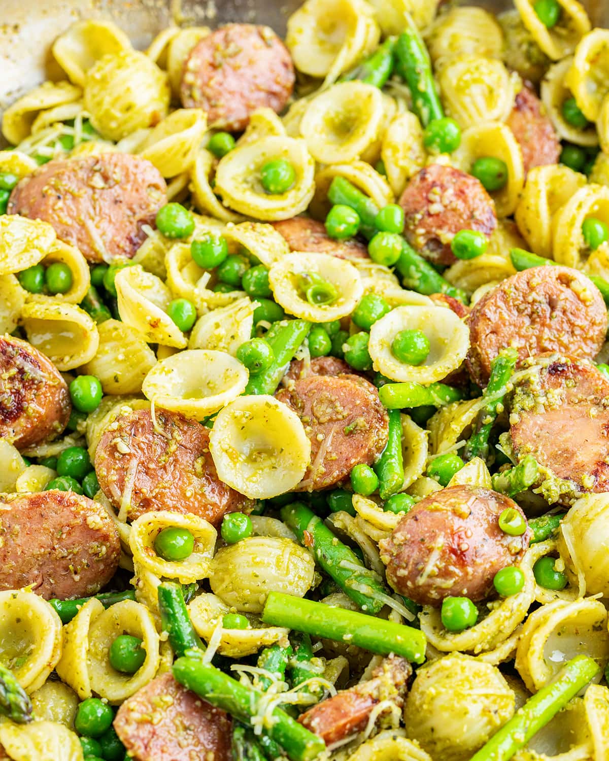 A pan of chicken orecchiette pasta with asparagus and peas.