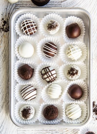 A metal pan topped with chocolate and white chocolate covered Oreo balls in rows in paper liners.