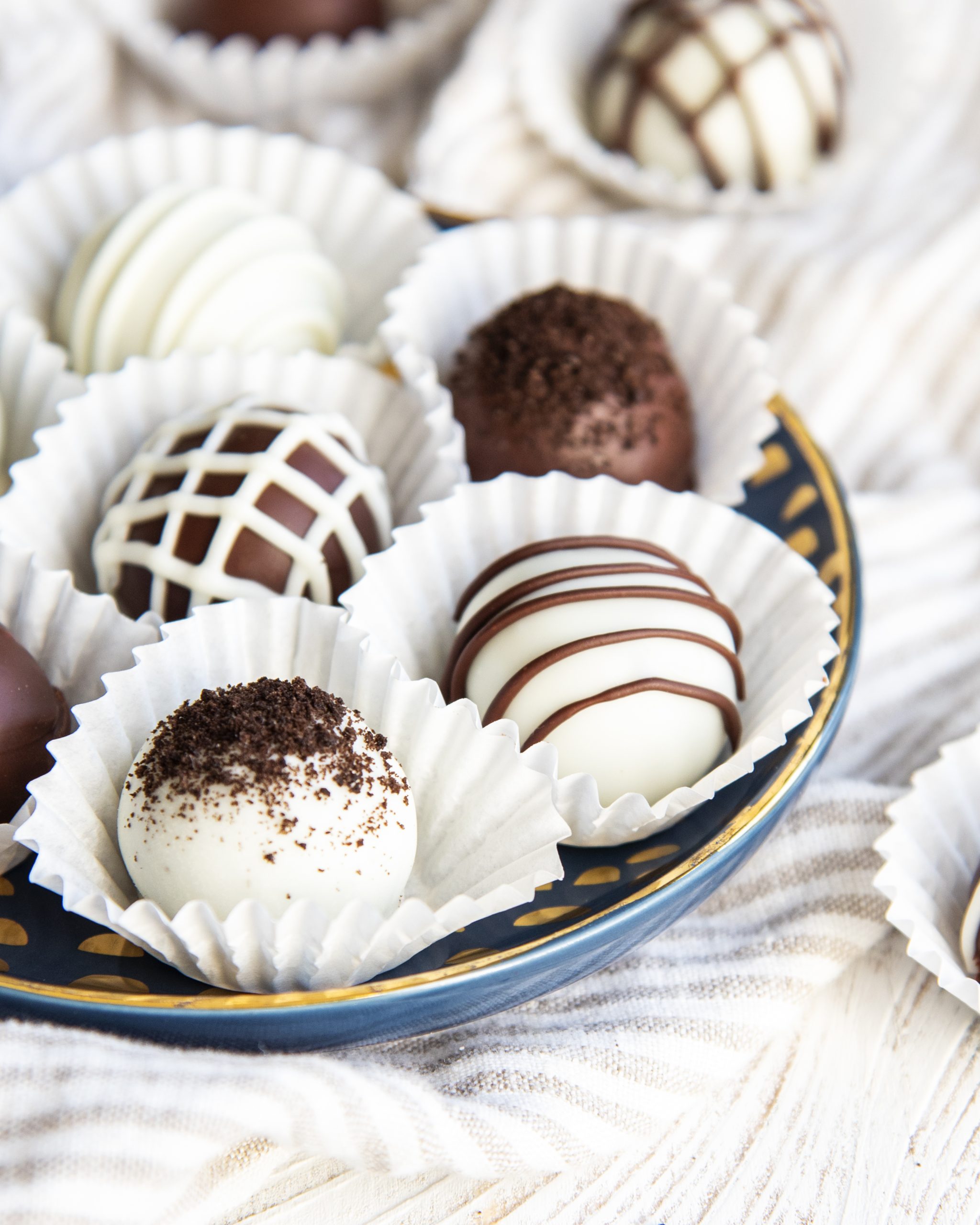 Oreo truffles set in paper liners, and decorated with Oreo crumbs and chocolate drizzle.