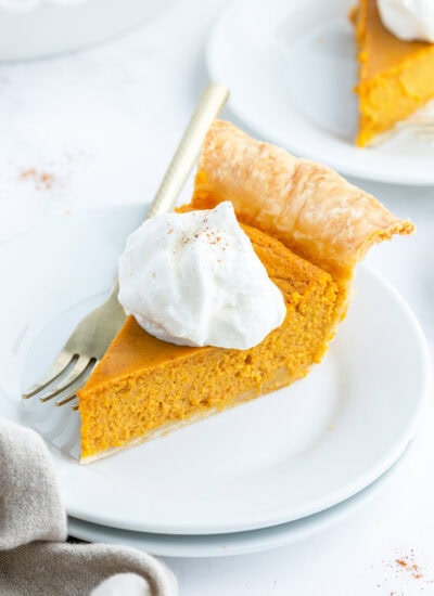 A piece of pumpkin pie topped with whipped cream.