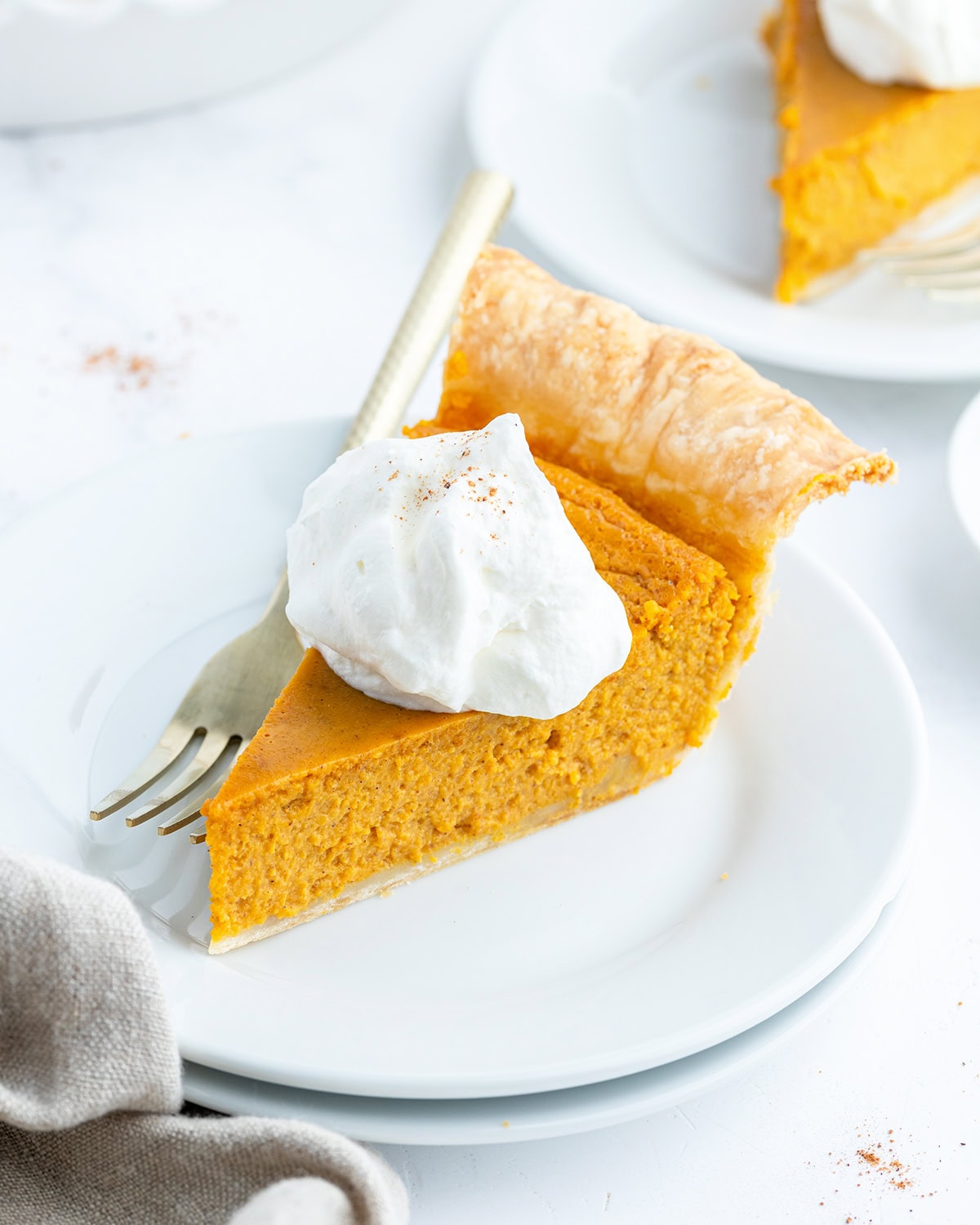 A piece of pumpkin pie topped with whipped cream.