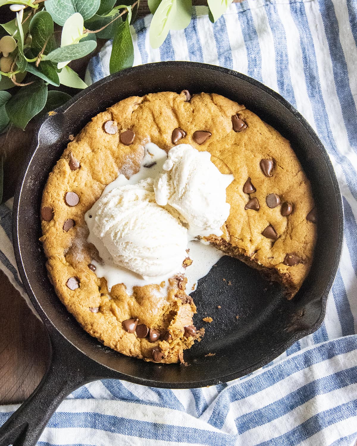 A pumpkin spice deep dish cookie in a skillet with a piece cut out.