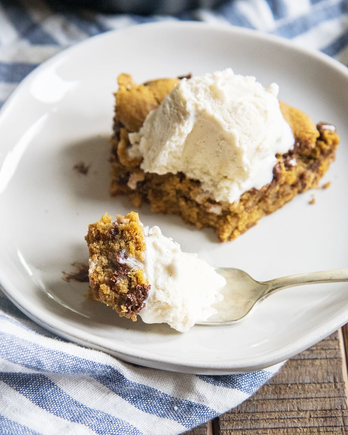 A slice of pumpkin pie skillet cookie on a plate with a bite on a fork.