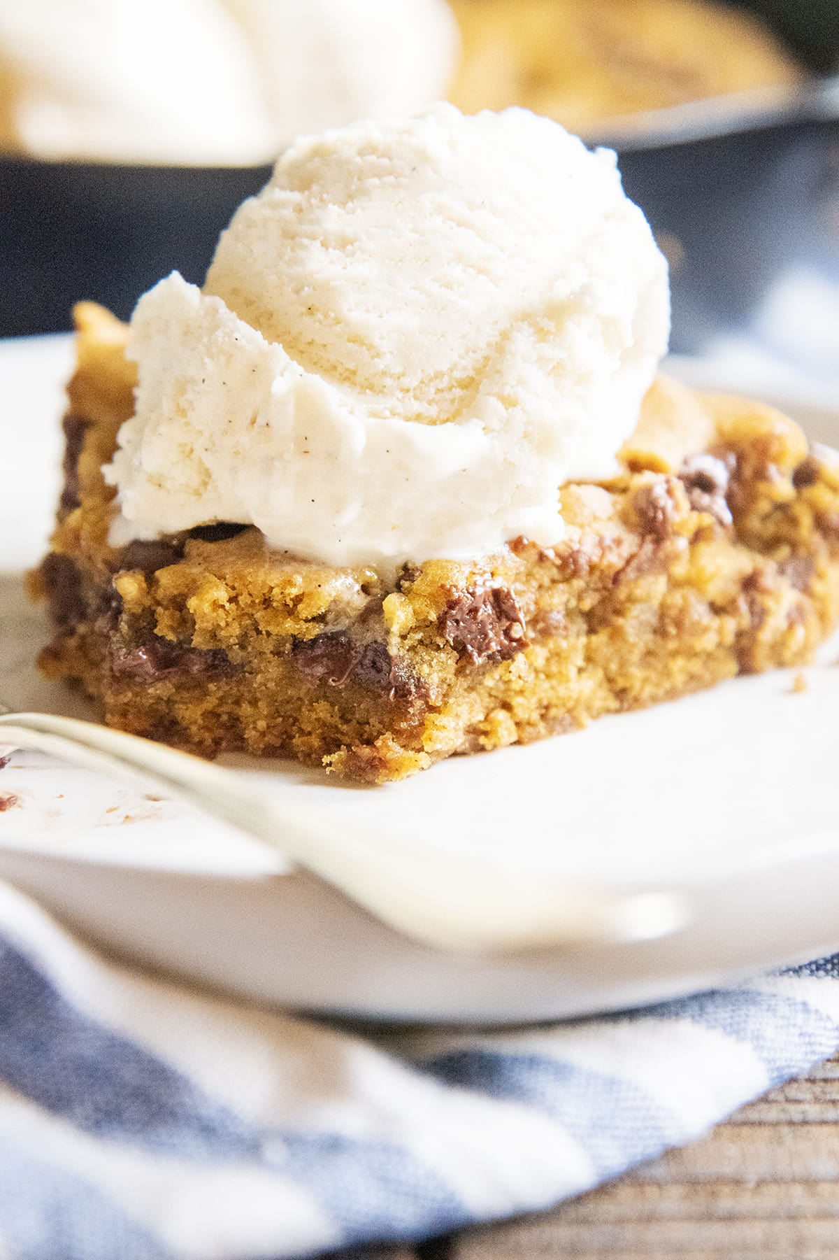 A piece of a pumpkin cookie cake with ice cream on top on a plate.