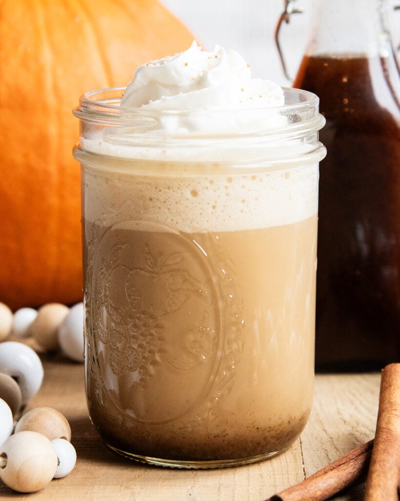 A homemade pumpkin latte in a mason jar topped with whipped cream.