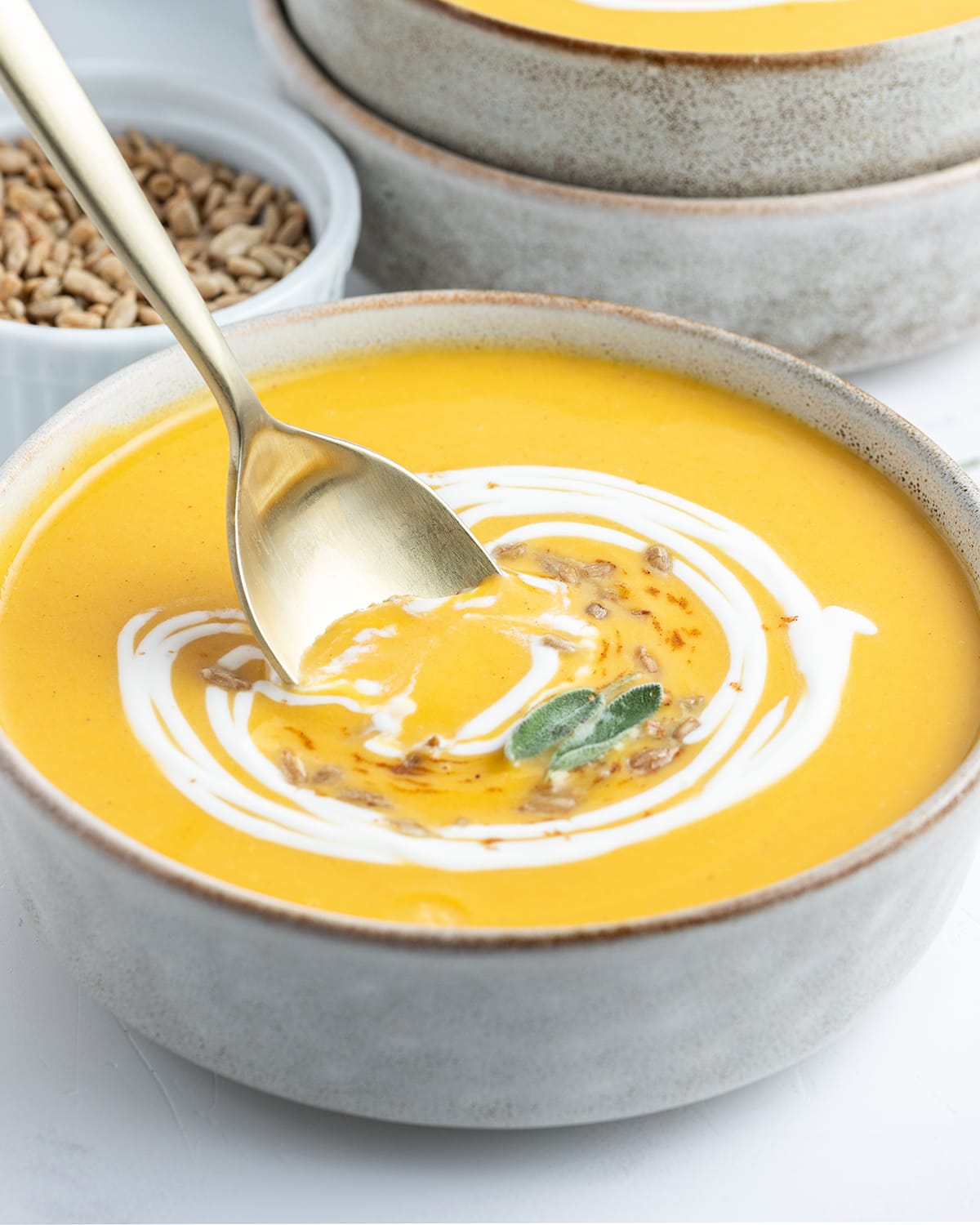 A spoon dipping into a bowl of butternut squash soup.
