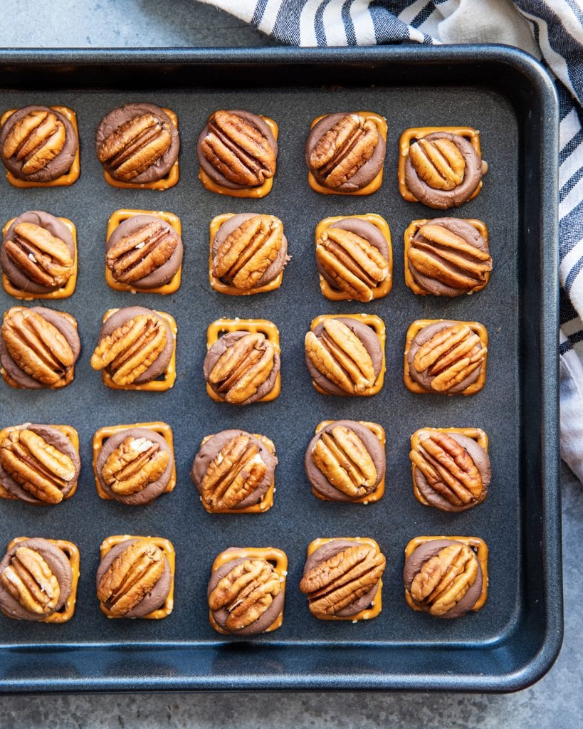 A baking pan full of pretzel rolo pecan turtles in rows.
