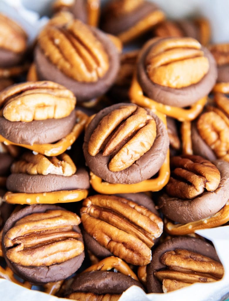 A pile or rolo pretzels topped with pecans.