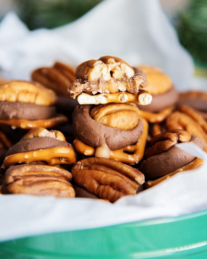 A pile of rolo pretzel turtles, and one has a bite out of it, showing the caramel.