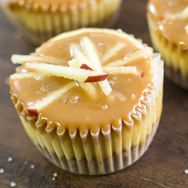 Close up view of salted caramel apple mini cheesecakes on a wood board.