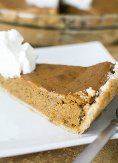 Front view of a slice of pumpkin pie on a white plate.