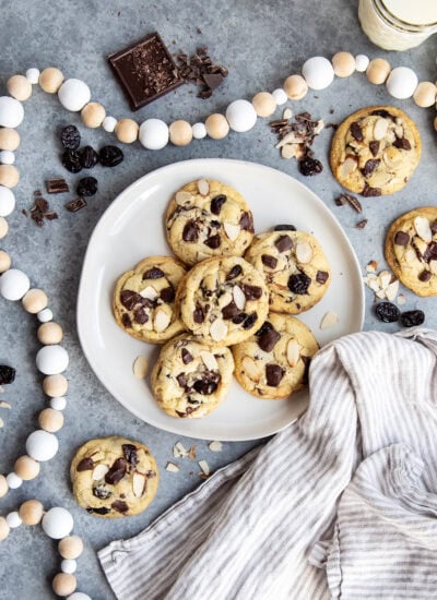 An above view of a plate of cherry almond chocolate chunk cookies with a tea cloth next to it.