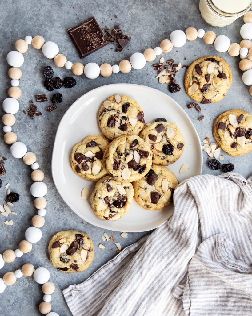 An above view of a plate of cherry almond chocolate chunk cookies with a tea cloth next to it.
