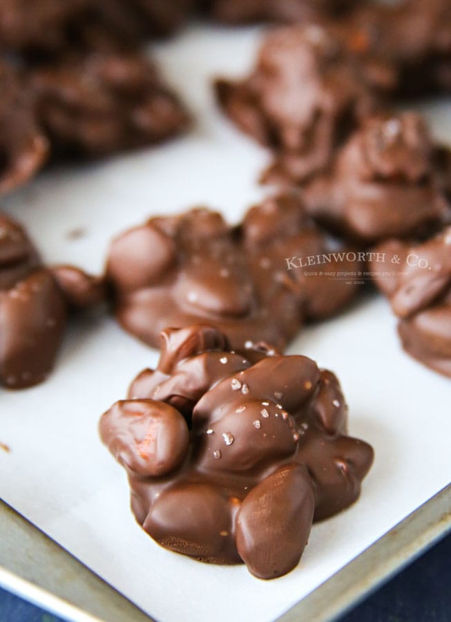 A baking pan of chocolate covered nut clusters topped with a sprinkle of sea salt.