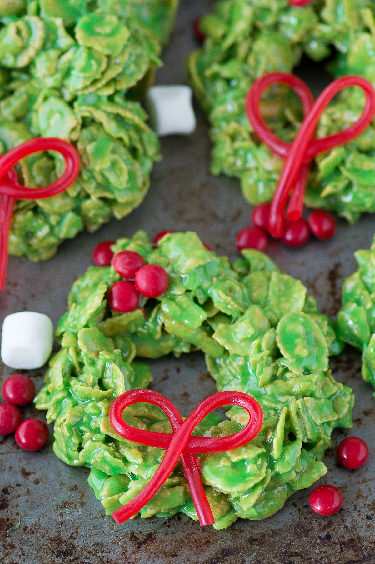 Christmas wreath cookies made with cornflakes covered in green marshmallows and shaped like wreaths.