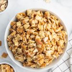 A large bowl of coconut chex mix, that is full of chex, golden grahams, sliced almonds, and shredded coconut.