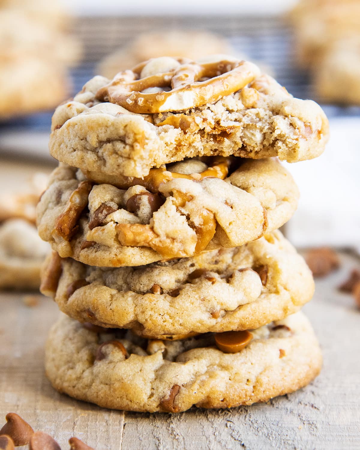 A stack of pretzel and cinnamon chip cookies with a bite taken out of the top cookie.