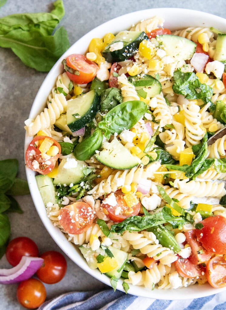 A pasta salad loaded with vegetables and topped with feta crumbles and fresh basil. 