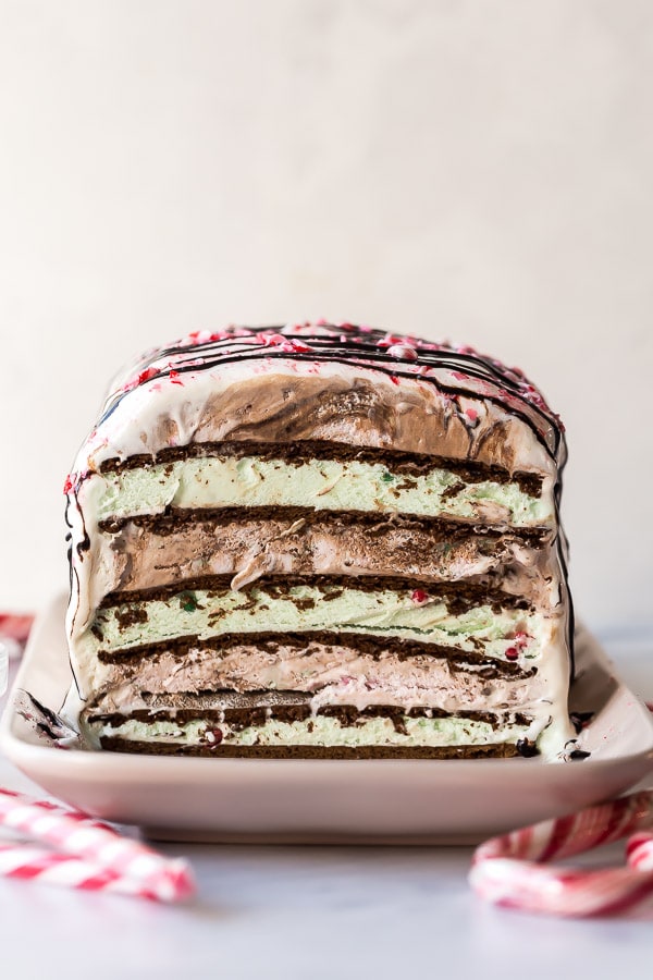 The inside of an ice cream sandwich cake showing layers of ice cream sandwiches, and ice cream, drizzled with chocolate.