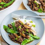 A plate of ground beef and snow peas on white rice.