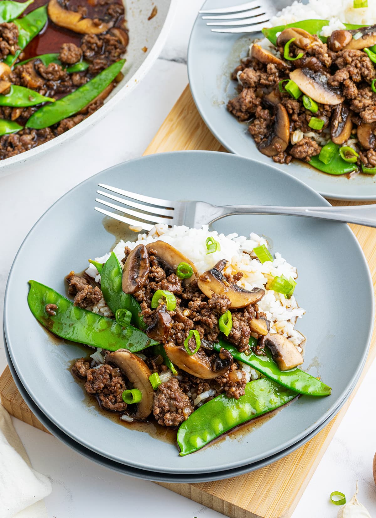 A plate of ground beef and snow peas on white rice.