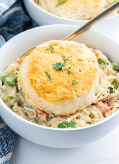 A bowl of chicken pot pie with a biscuit on top.