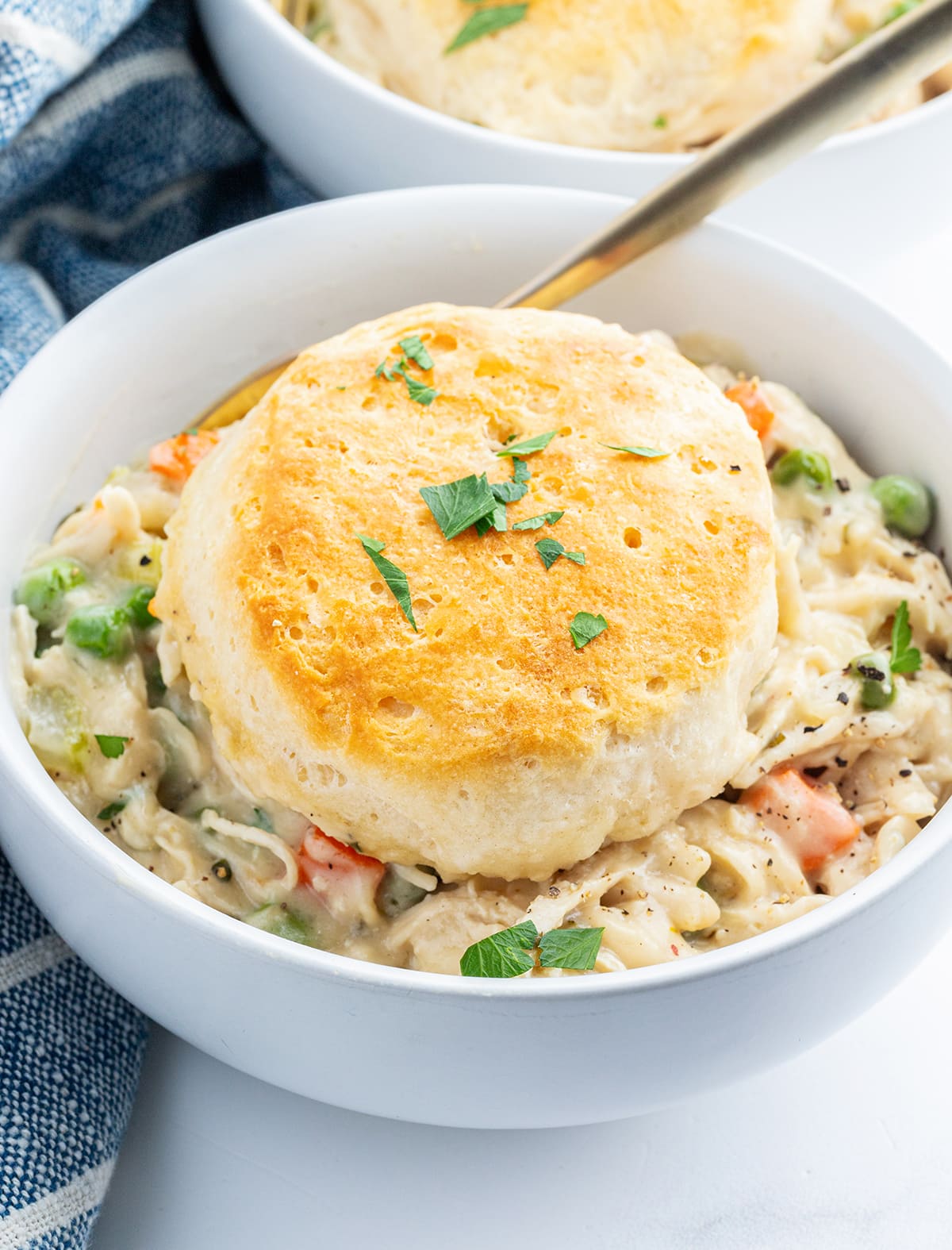 A bowl of chicken pot pie with a biscuit on top.