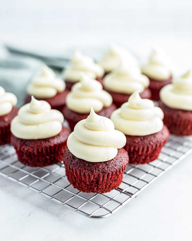 Cream Cheese Frosting on top of red velvet cupcakes in swirls.