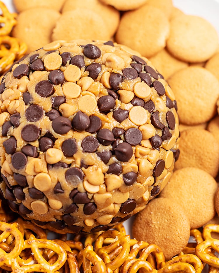 A close up shot of a peanut butter ball coated in peanut butter chips and chocolate chips, surrounded by nilla wafers.