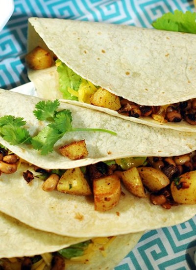 Top view of potato black-eyed pea tacos on a blue and white plate.