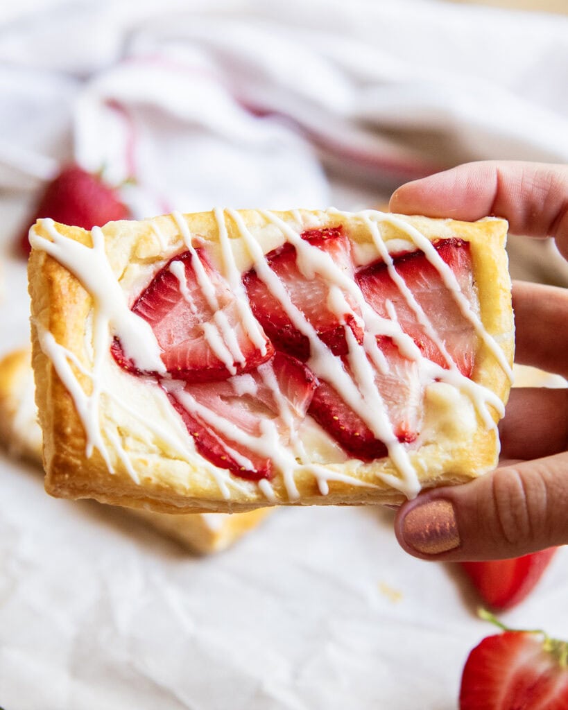 A hand holding a strawberry pastry.