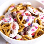 Close up image of valentine's day pretzels dipped in white chocolate and topped with sprinkles in a bowl.