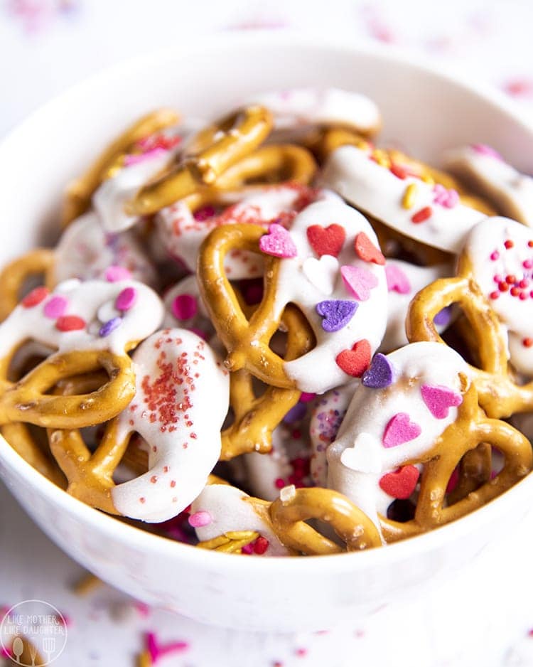 Close up image of valentine\'s day pretzels dipped in white chocolate and topped with sprinkles in a bowl.
