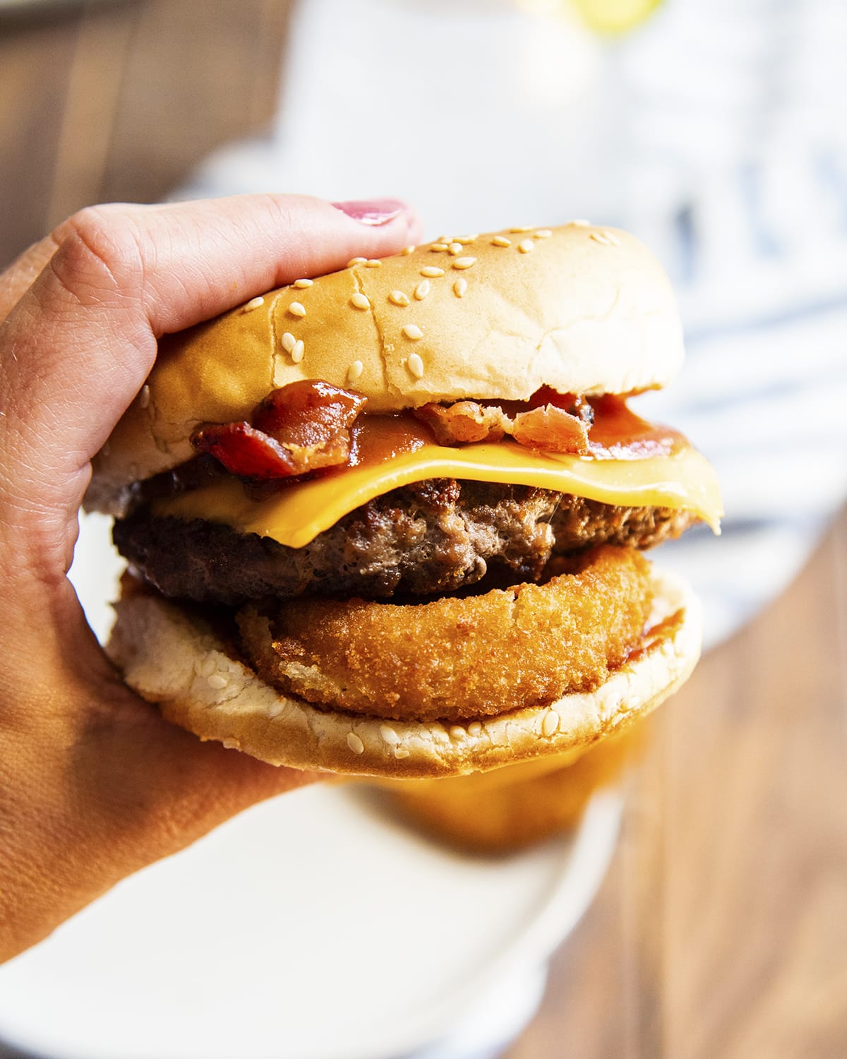 A hand holding a Western Bacon Cheeseburger.