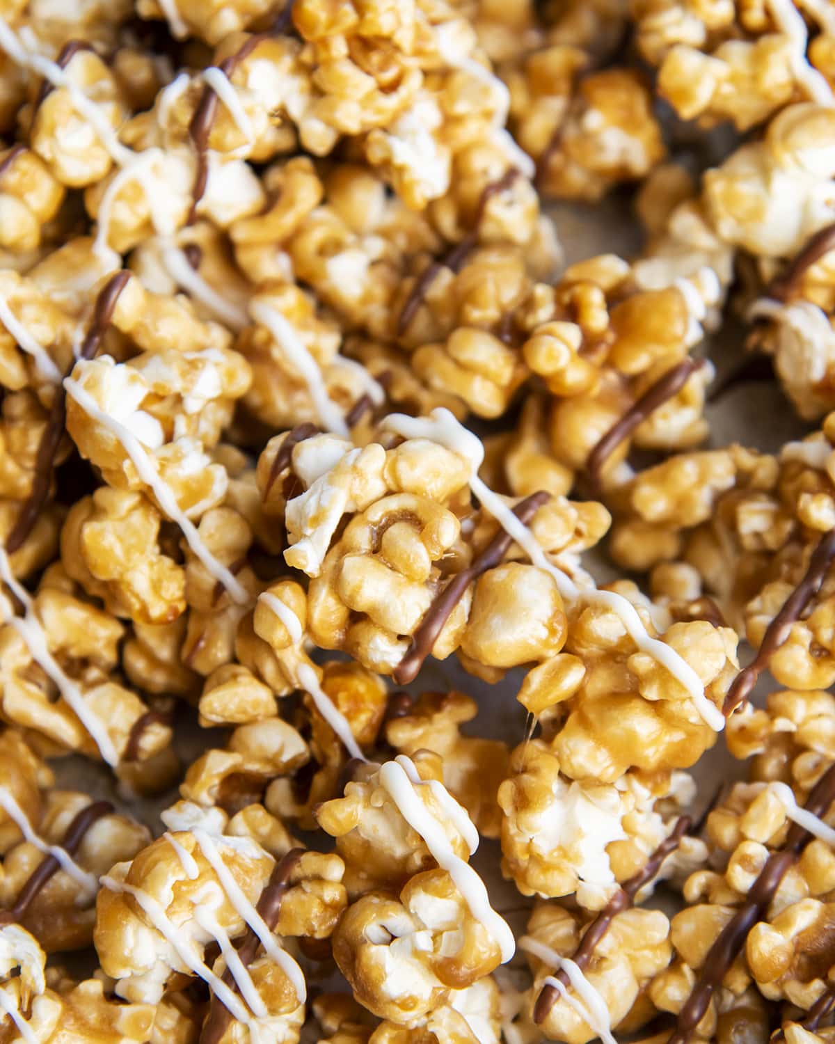 A close up of caramel popcorn topped with white chocolate and chocolate drizzles.