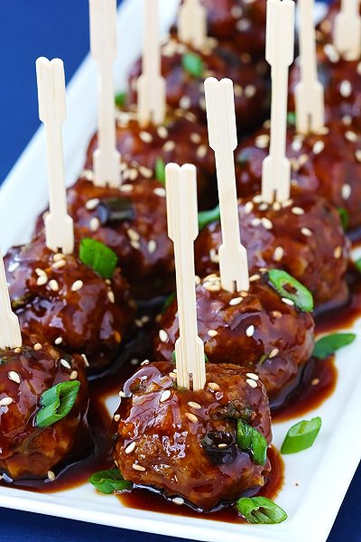 Angled view of asian meatballs with small wood forks in them.