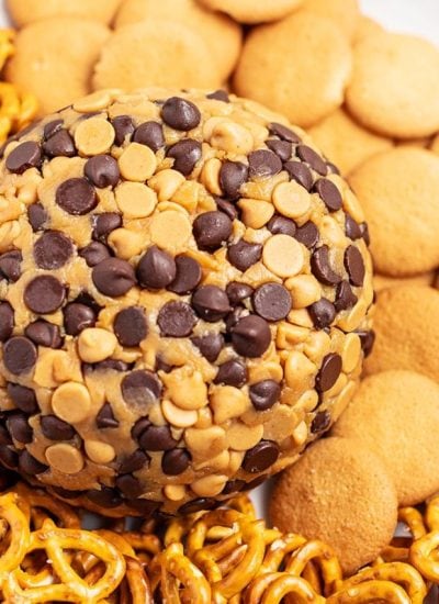 A close up shot of a peanut butter ball coated in peanut butter chips and chocolate chips, surrounded by nilla wafers.