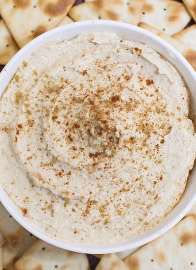 Top view of a bowl of homemade hummus surrounded by pita chips.