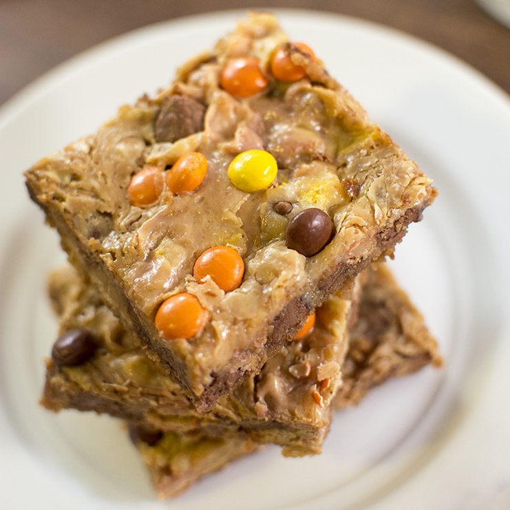 Top view of a stack of reeses pieces magic bars on a white plate.