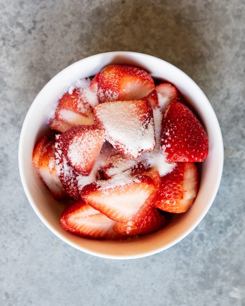 A bowl of sliced strawberries sprinkled with sugar.