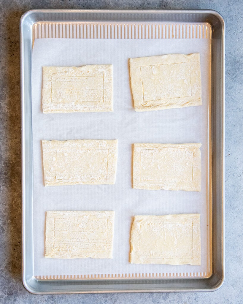 An above photo of pieces of puff pastry, with a square scored out in the middle.