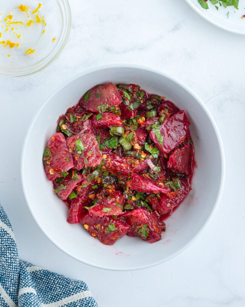 A bowl of blood orange pieces topped with cilantro.