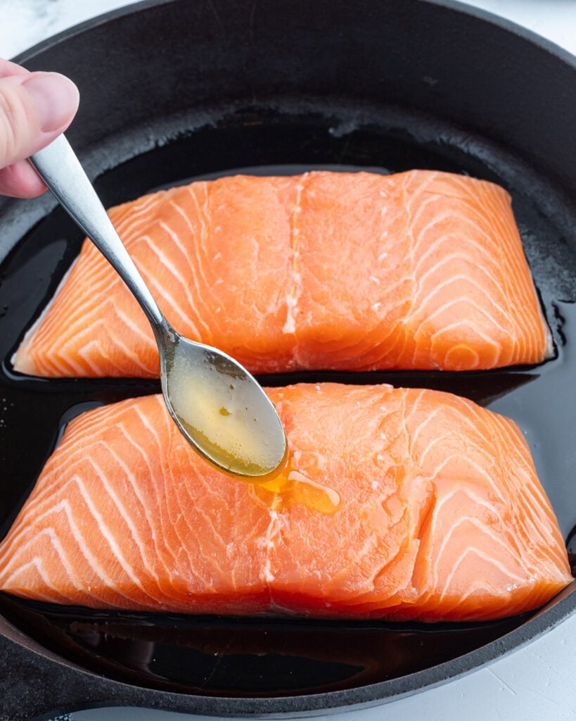 Two salmon fillets in a cast iron skillet.