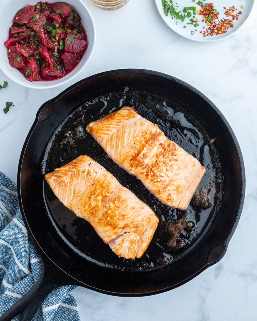 Two baked salmon fillets in a skillet.
