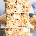 A stack of three rice krispie treats with parchment paper between them.