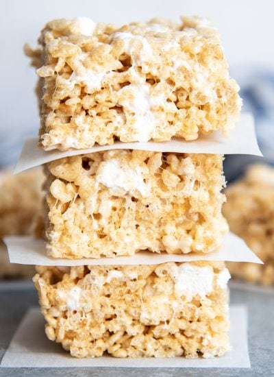 A stack of three rice krispie treats with parchment paper between them.