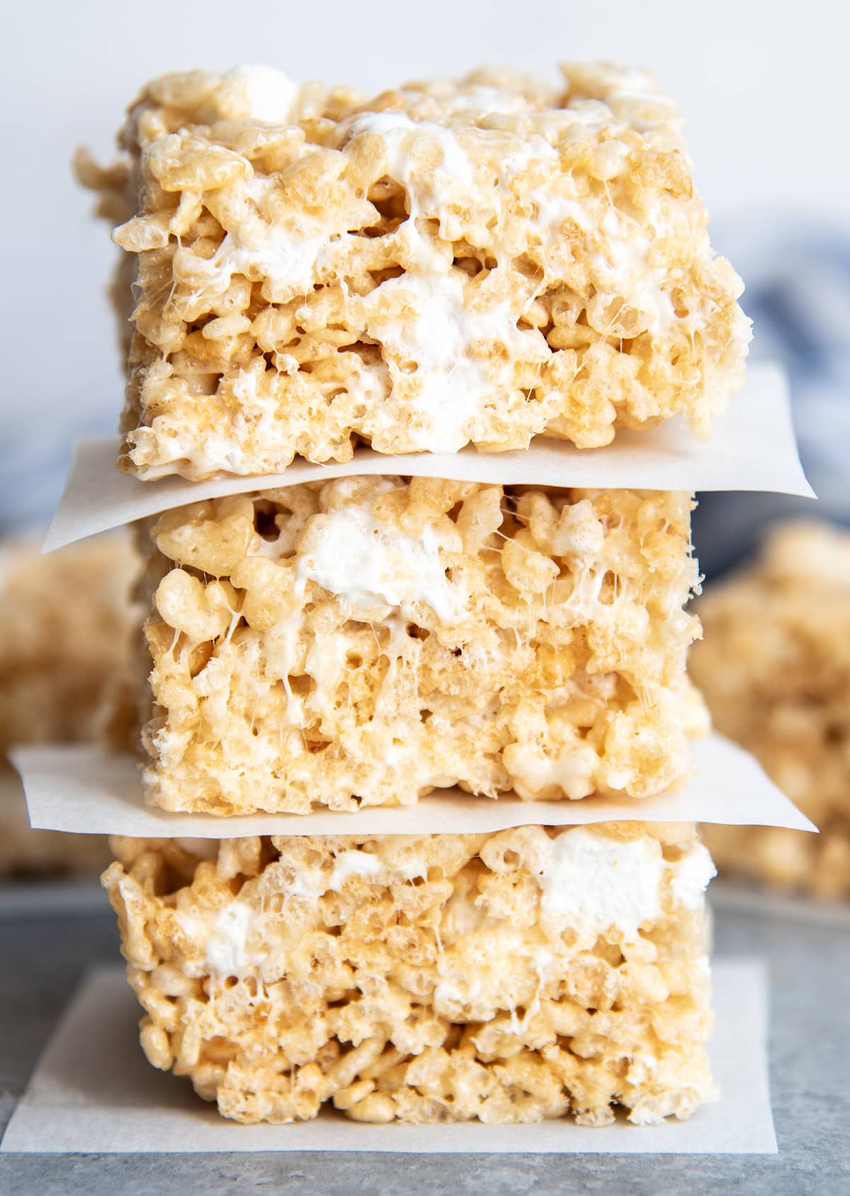 A stack of three rice krispie treats with parchment paper between them.