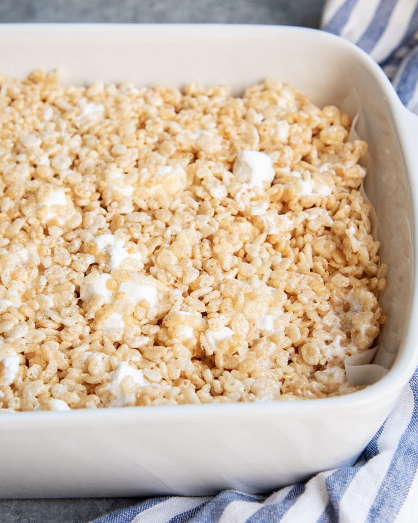 A pan of rice krispie treats with extra whole marshmallows speckled around the treats.