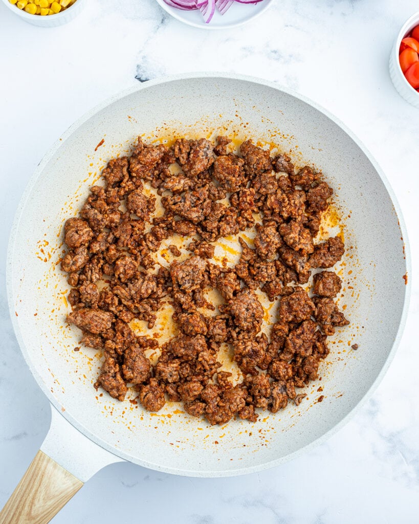 A white skillet of seasoned ground beef. 